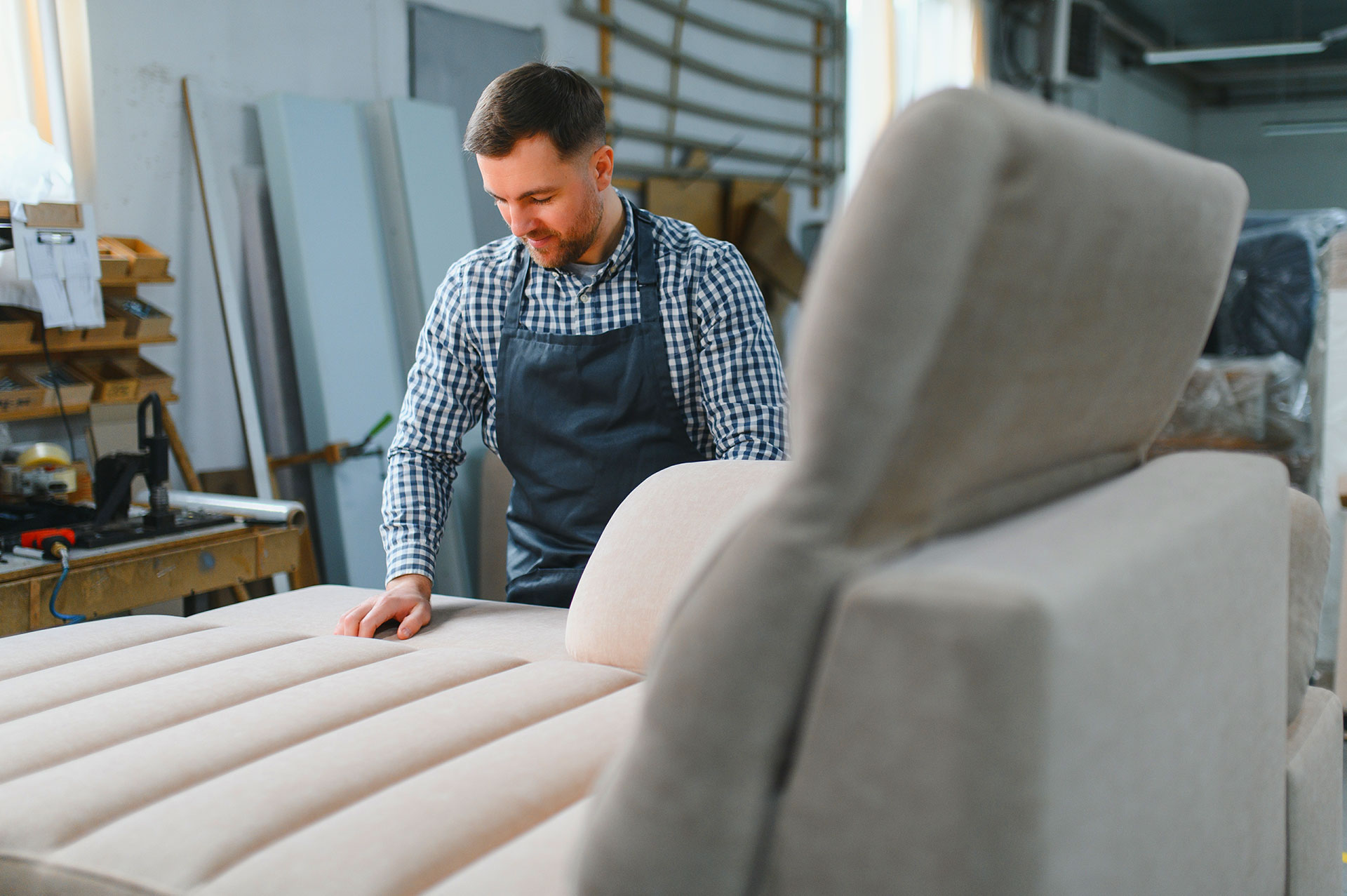 Upholstery craftsman smoothing fabric on sofa in workshop